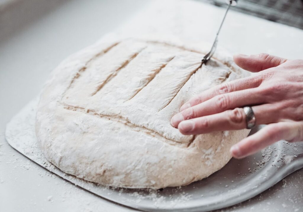 Mjölad bröddeg snittas med kniv före gräddning